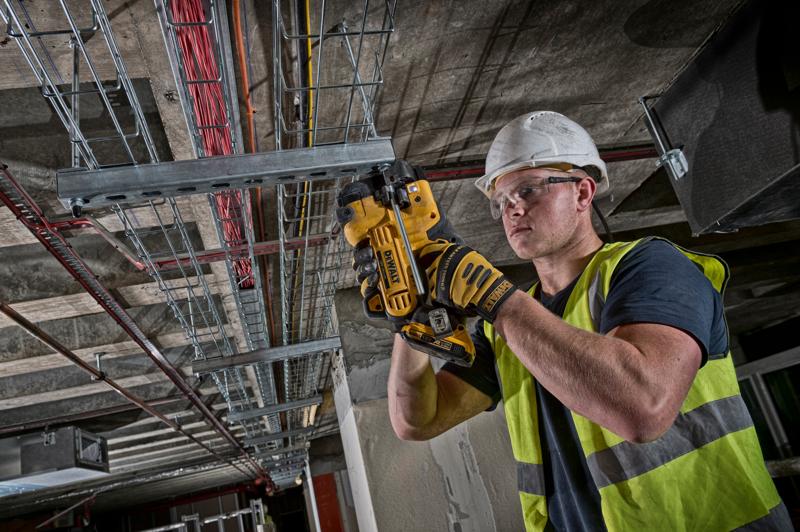 Arbeiter schneidet mit DEWALT DCS350NT Metallrohr an einer Deckeninstallation.