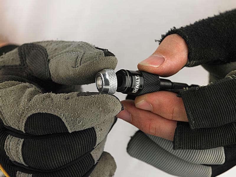 Behandschuhte Hände halten einen DEWALT Bit-Halter.
